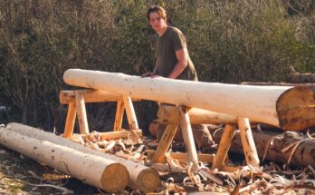 Man peeling logs with a drawknife to build a log cabin